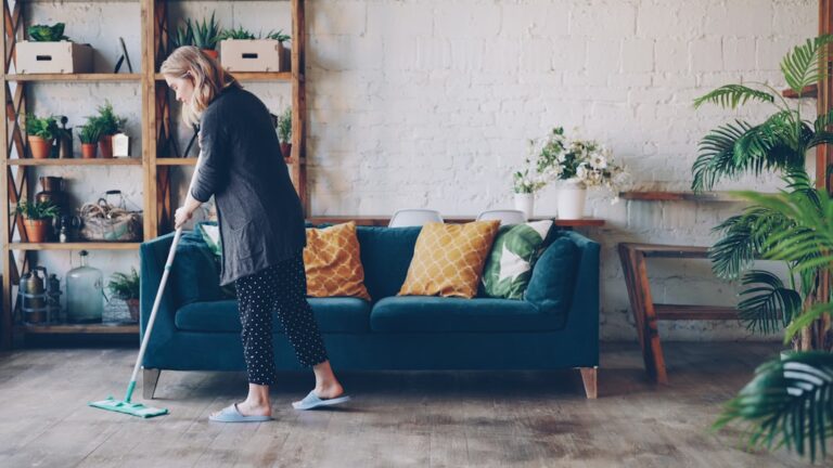 Cleaner mopping the floor of a bright, modern living room during a home cleaning visit