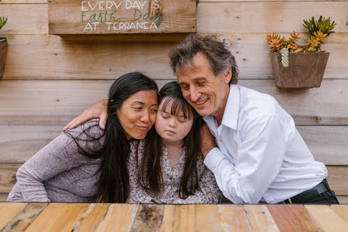 A family warmly embraces their daughter, showing love and support in an outdoor setting.
