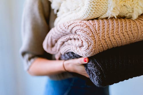 Lady carrying freshly folded woollen clothes