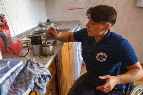 Individual in a wheelchair making coffee, showcasing independence and daily living.