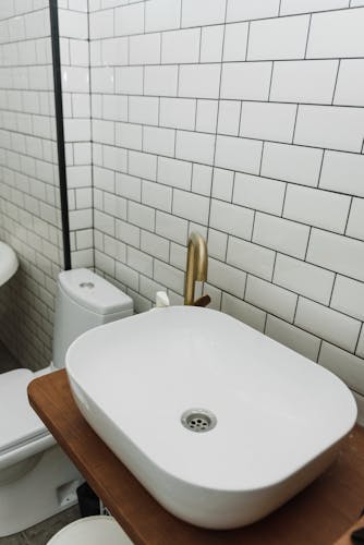 Stylish bathroom featuring a white ceramic sink with gold faucet and classic subway tiles.
