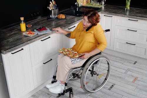 Woman using wheelchair prepares breakfast in kitchen, showing inclusivity.